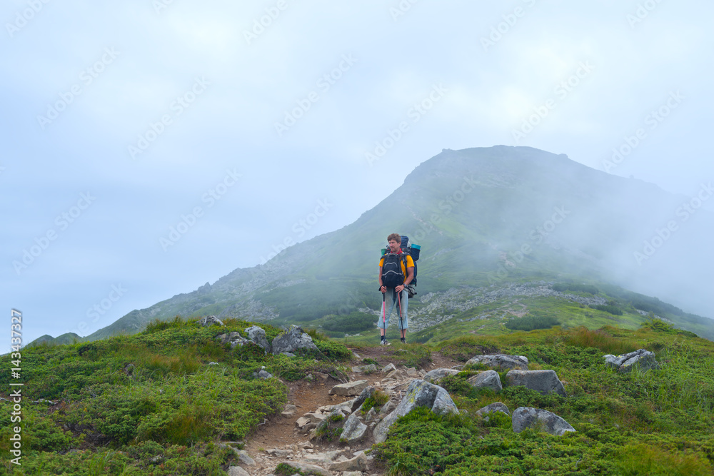 Man, traveler with big backpack goes the mountain trail