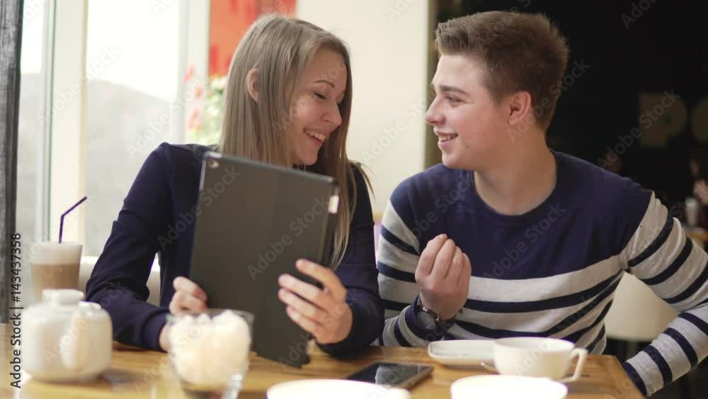 Young couple sitting in cafe, using digital tablet, watching movies and shopping Young couple sitting in cafe, using digital tablet, watching movies and shopping