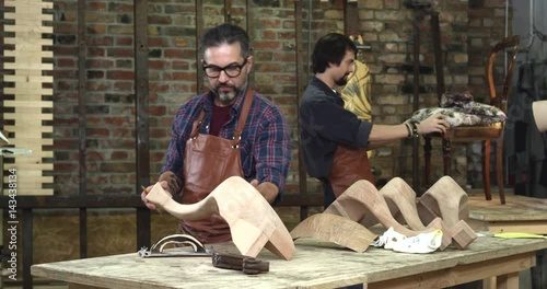 Family Joiner’s Shop/Busy family joiner’s shop. Here work of  fine wood is made. The experienced worker make final touches to the table cabrioli legs in the style of Louis XV and Queen Anne photo