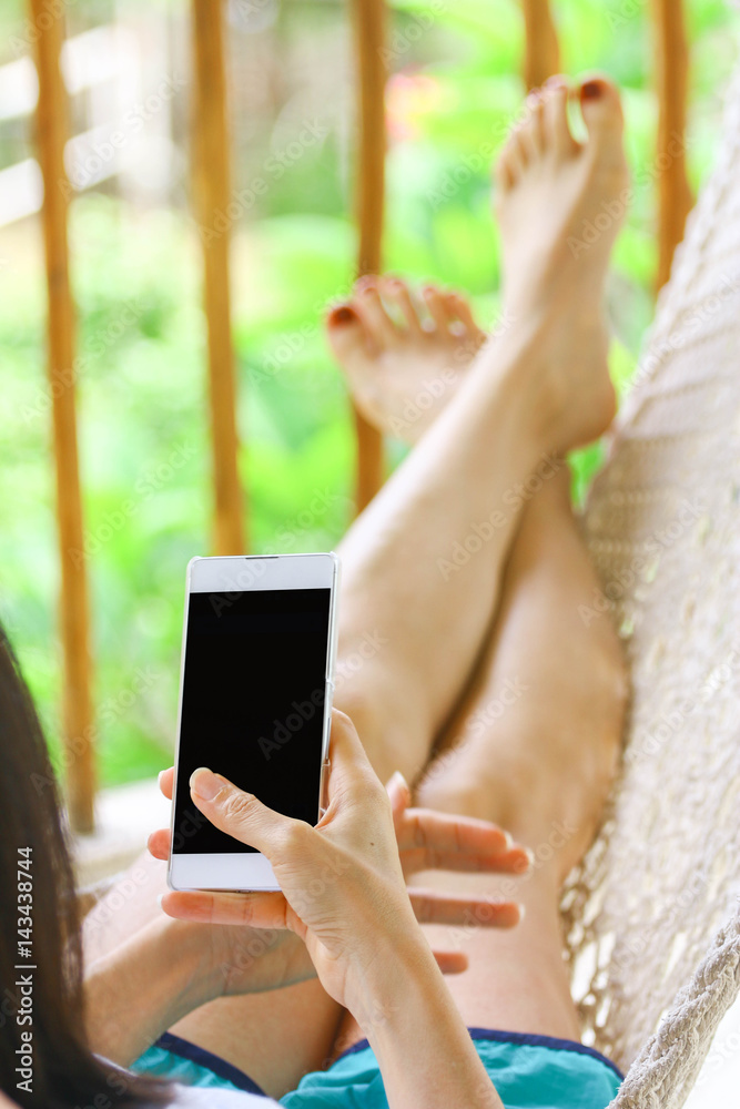 young women using mobile smart phone while relaxing in a cradle