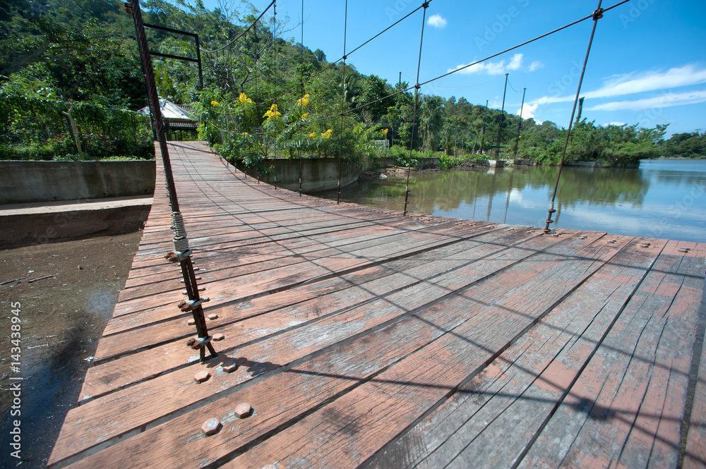 Wire hanging bridge with wooden pathway in Thailand.
