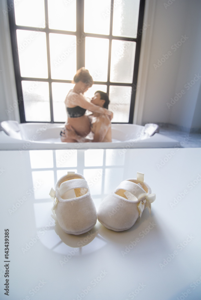 Φωτογραφία baby shoes and blur pregnant woman with her husband background