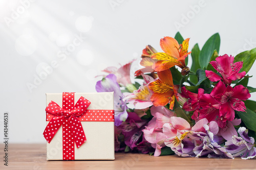 Gift box with spring flowers on wooden table, white background photo