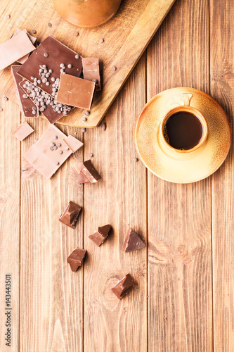 Chunks of chocolate on a brown wooden background, selective soft focus, vertical 