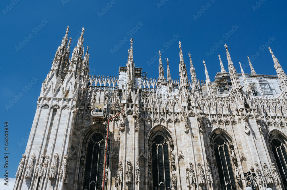 MILAN, ITALY - JUNE 17, 2016: Workers on walls of Duomo di Milano, main tourist attraction. Cleaning and repairing white marble exterior is a continuous process.