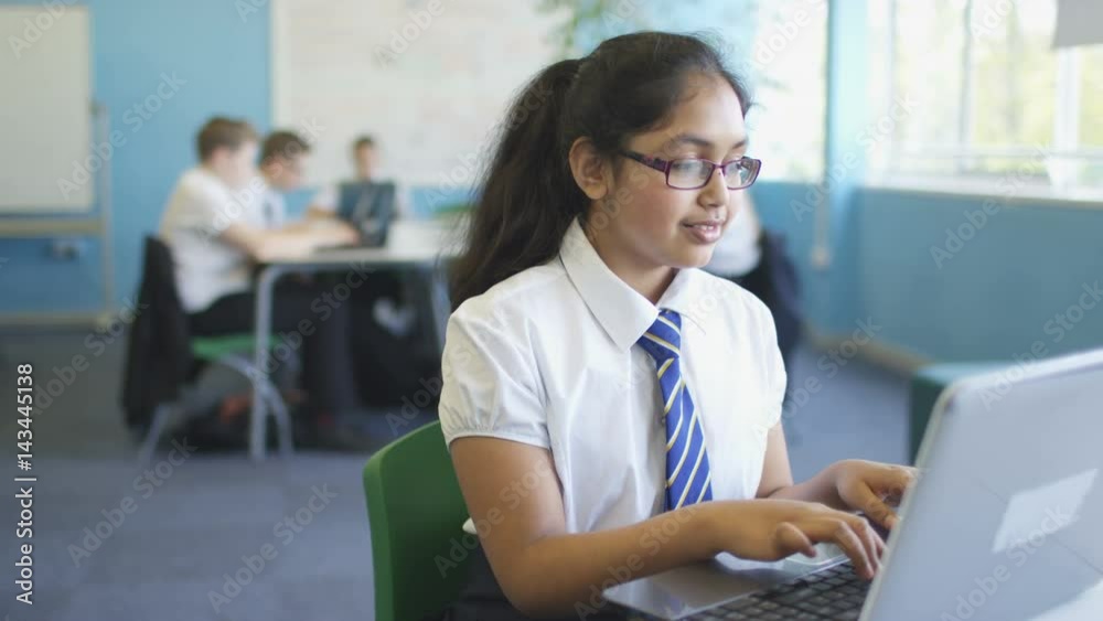  Portrait smiling school girl working on laptop in classroom