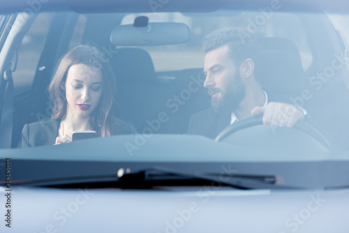 Business couple having a conversation while driving a car. Front view through the windshield © rh2010