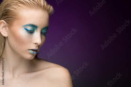 Cold at heart. Studio portrait of a blonde female model wearing professional makeup in blue shades posing on violet background looking away copyspace on the side