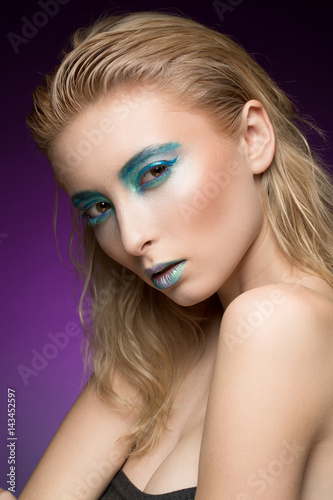 Hot and cold. Vertical cropped shot of a blonde fashion model wearing futuristic blue shaded makeup with metallic lips looking to the camera fiercely