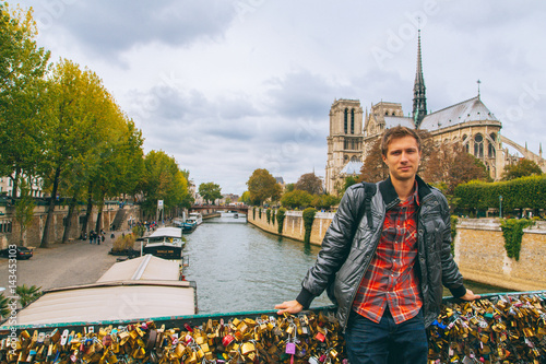 Young man standing on the love bridge in Paris by the Notre Dame.