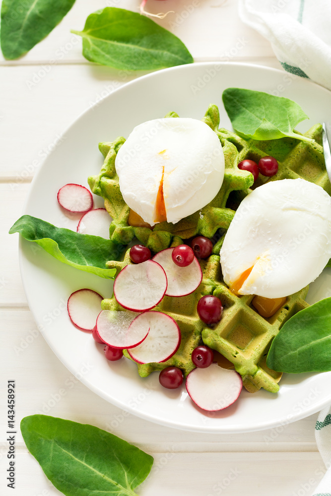 Healthy breakfast: spinach waffles with radish slices and poached eggs on white wooden table. Selective focus Healthy breakfast: spinach waffles with radish slices and poached eggs on white wooden table. Selective focus