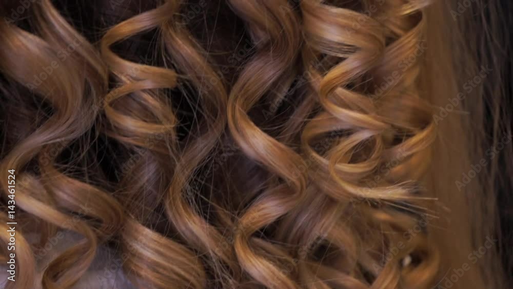 Hair stylist making curls on customer hair using electric curler