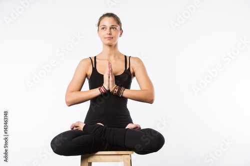 beautiful woman sit on a chair in meditative pose isolated on white