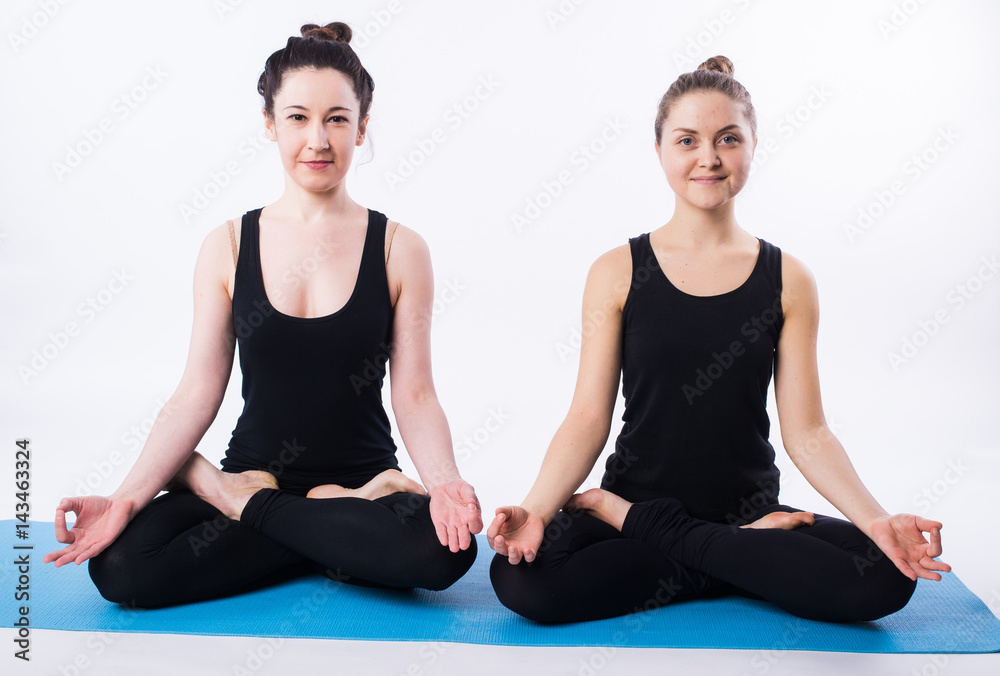 Young man and woman doing yoga and meditating in lotus position isolated on white background. Young man and woman doing yoga and meditating in lotus position isolated on white background.