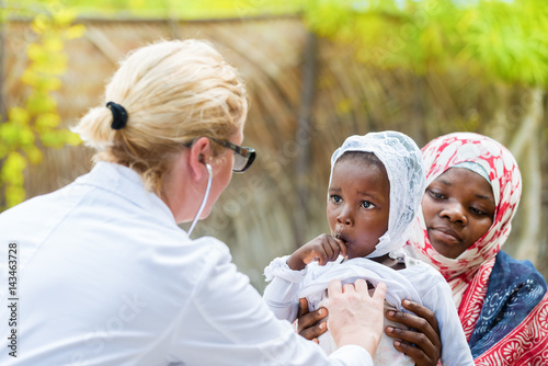Papier peint Female Caucasian doctor listening heart beat and breathing of little African girl with stethoscope