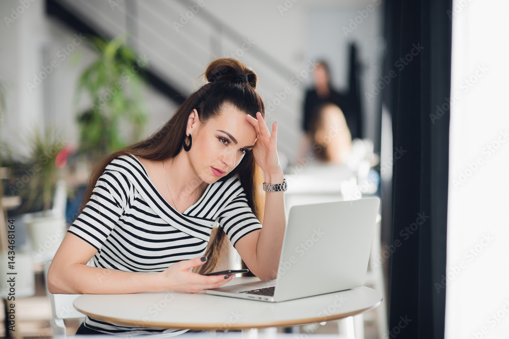 Woman sitting in a cafe in front of a laptop thinking about a problem with her hands touching head. Adult lady trying to find solution. Woman sitting in a cafe in front of a laptop thinking about a problem with her hands touching head. Adult lady trying to find solution.