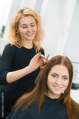 Changing looks. Vertical shot of a beautiful smiling hairdresser styling the hair of her client