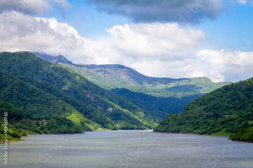 nature landscape in summer time. summer scenery with a calm lake surrounded by hills with green trees, woods, forest. outdoors background, nature in summer with blue sky and clouds 