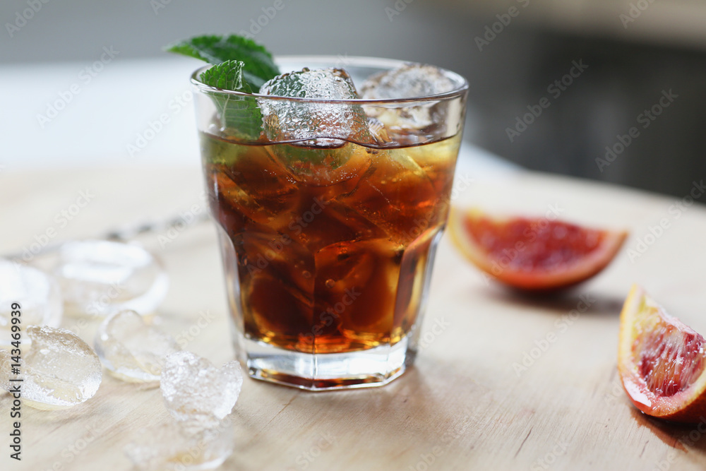 Cocktail whiskey cola with ice in a glass. On a wooden board are fragments of fruit. Photo with depth of field. Cocktail whiskey cola with ice in a glass. On a wooden board are fragments of fruit. Photo with depth of field.