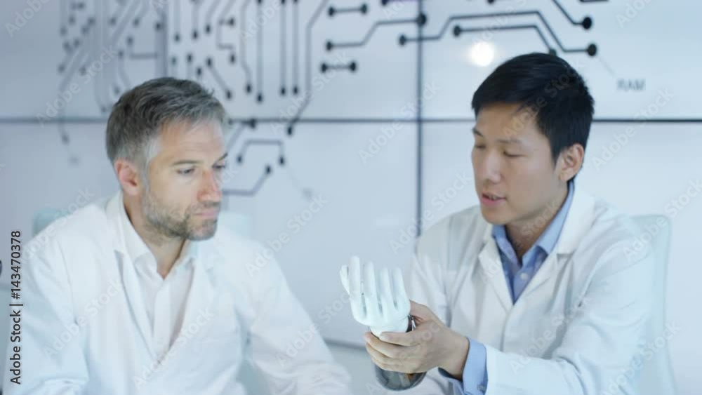 Scientific research engineers collaborating on project to build robotic hand Scientific research engineers collaborating on project to build robotic hand