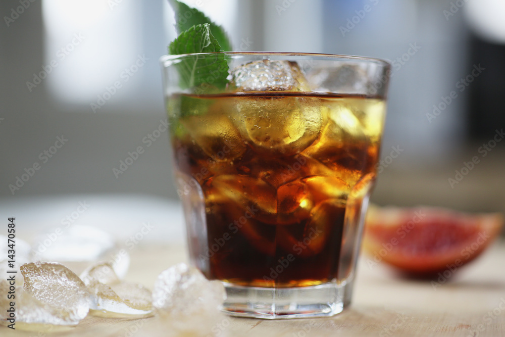 Cocktail whiskey cola with ice in a glass. On a wooden board are fragments of fruit. Photo with depth of field. Cocktail whiskey cola with ice in a glass. On a wooden board are fragments of fruit. Photo with depth of field.