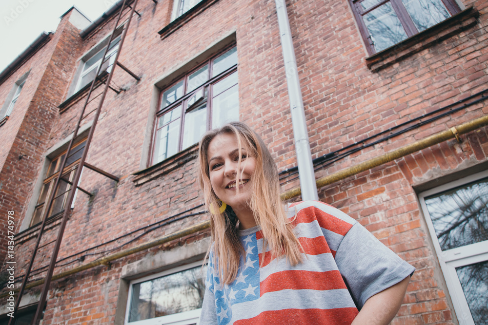 A hipster girl in an old courtyard posing and smiling A hipster girl in an old courtyard posing and smiling