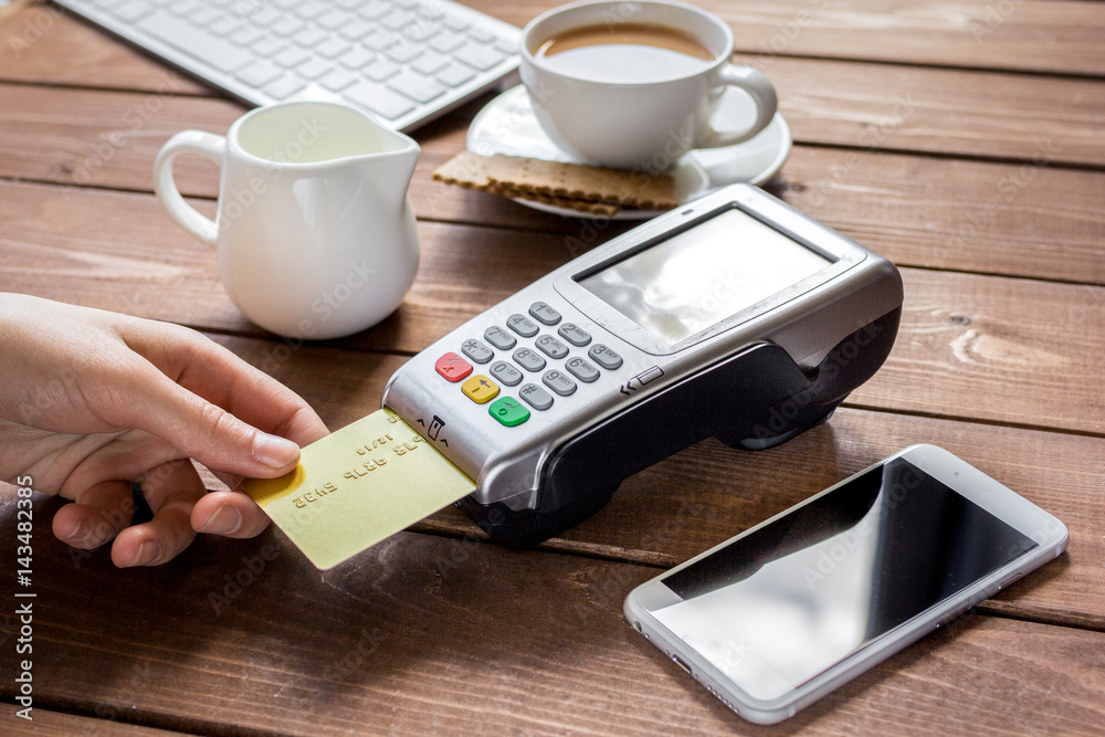 Payment for breakfast with card and terminal on wooden table background Payment for breakfast with card and terminal on wooden table background