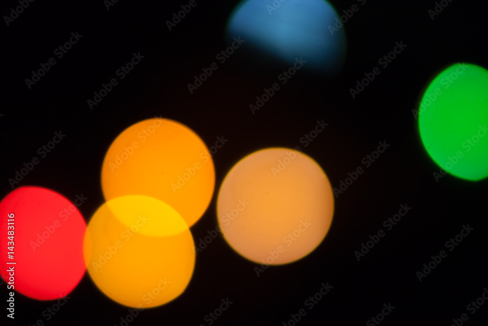 Colorful abstract blurry defocused bokeh lights on black background. Green, orange and red spots