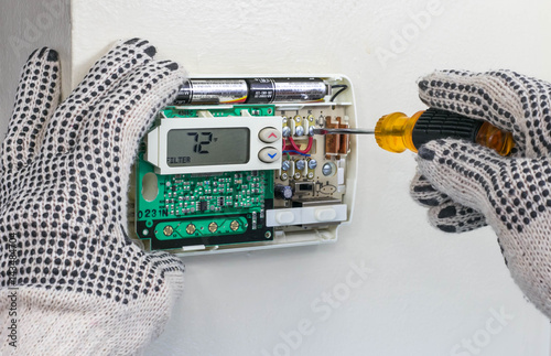 HVAC Technician Installing Digital Heating and Cooling Thermostat