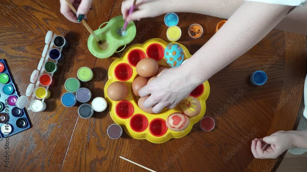 Mom and daughter are preparing for Easter. paint eggs. Top view Mom and daughter are preparing for Easter. paint eggs. Top view