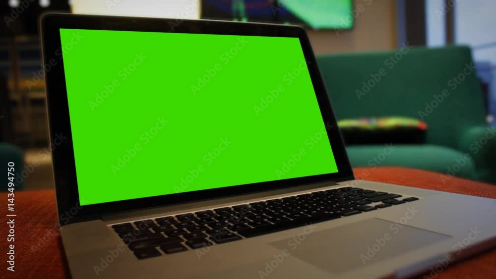 Generic Laptop in hotel lobby waiting room area with green screen for corner pin Generic Laptop in hotel lobby waiting room area with green screen for corner pin