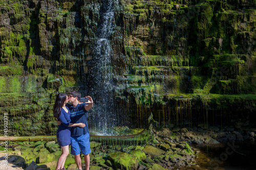 Mixed race couple take selfies at waterfall © Colin