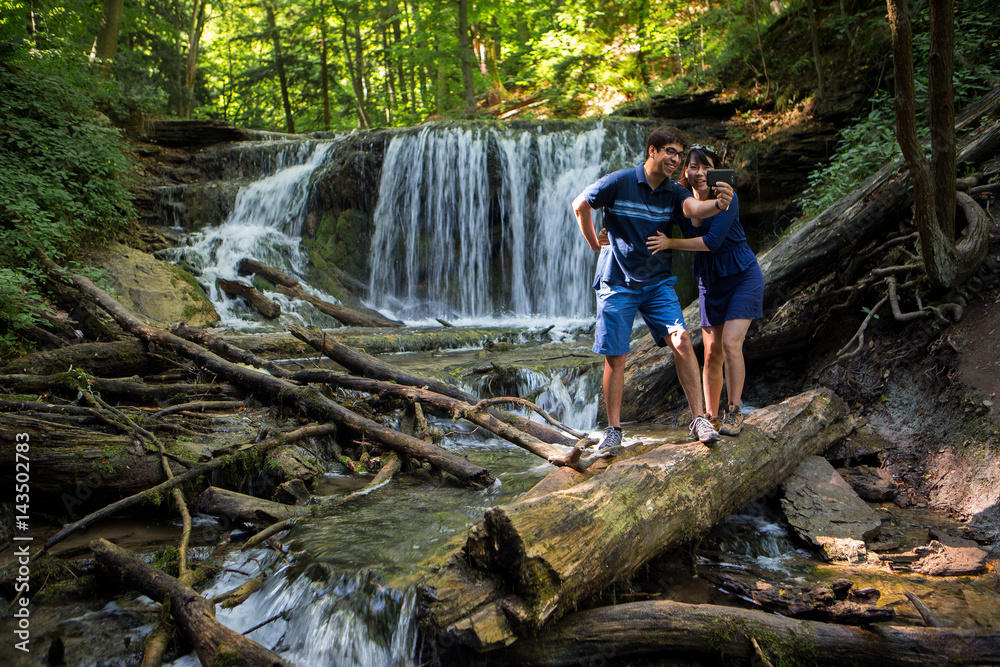 Mixed race couple take selfies at waterfall