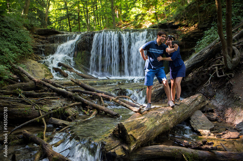Obraz na płótnie Mixed race couple take selfies at waterfall w salonie