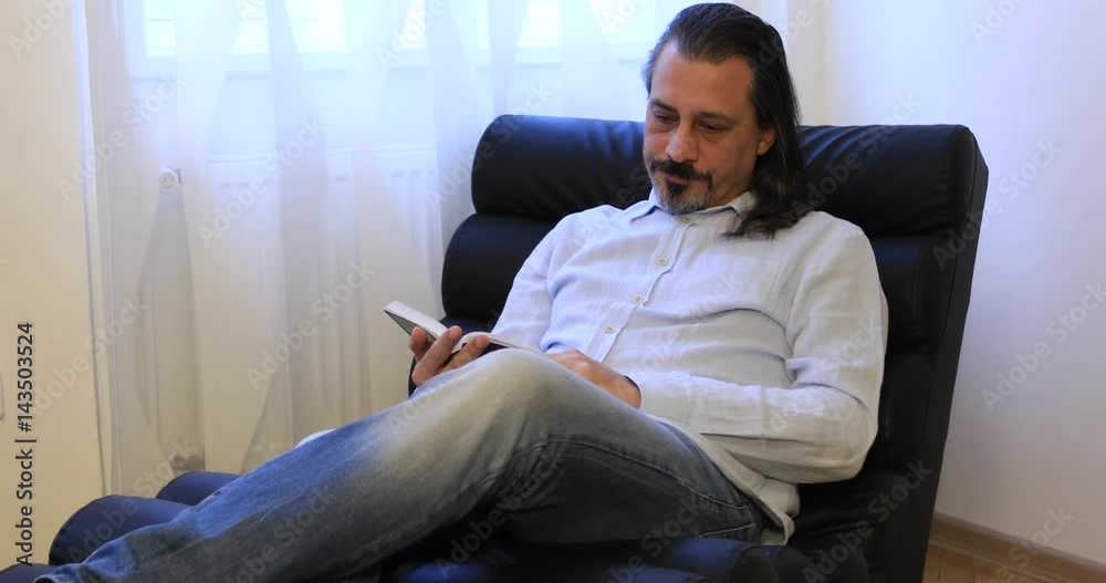 attractive middle age man reading a book at home attractive middle age man reading a book at home