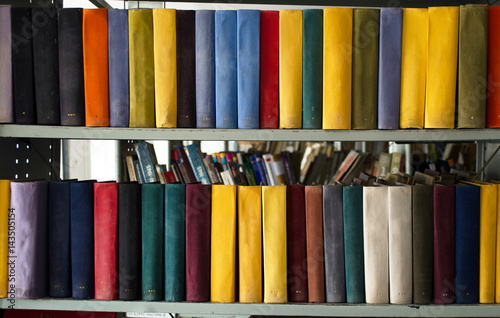 Stack of colored old books on a bookshelf in the library. Front view. Education concept.