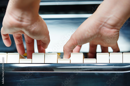 Scene of pianist hands from underneath angle playing piano.