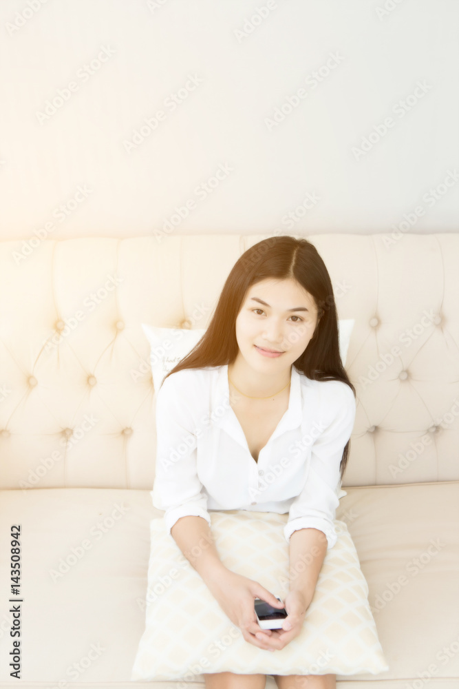 Pretty girl using her smartphone on couch at home in the living room