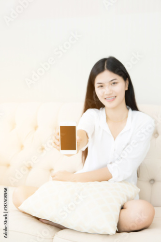 Pretty girl using her smartphone on couch at home in the living room