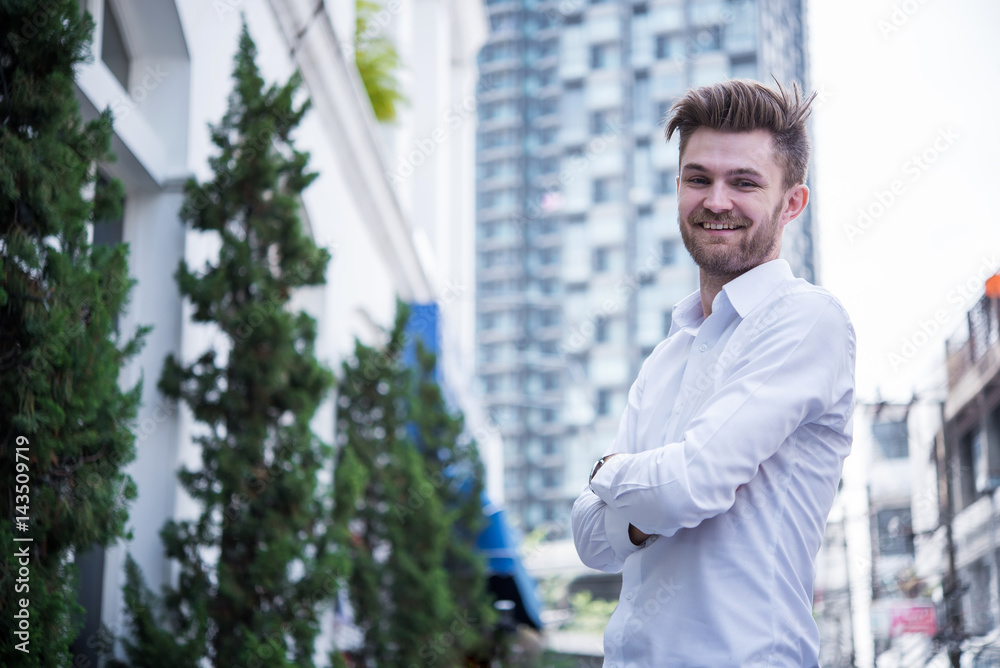 Young Business man standing in front of office with building background Young Business man standing in front of office with building background