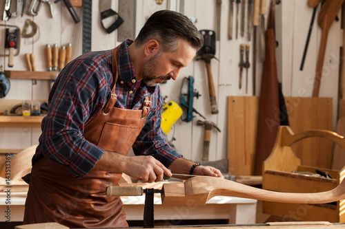 Joiner Makes Cabriole Leg for Vintage Table/Carpenter works with a planer in a workshop for the production of vintage furniture. He makes cabriole leg for a table in the style of Queen Anne