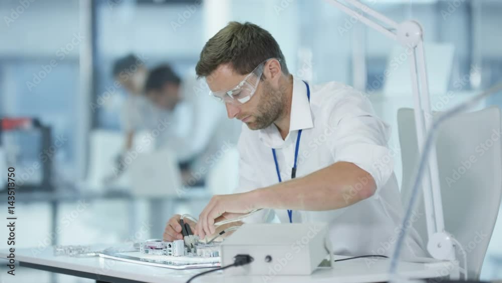Electronics engineer working in lab building & testing electronic devices Electronics engineer working in lab building & testing electronic devices