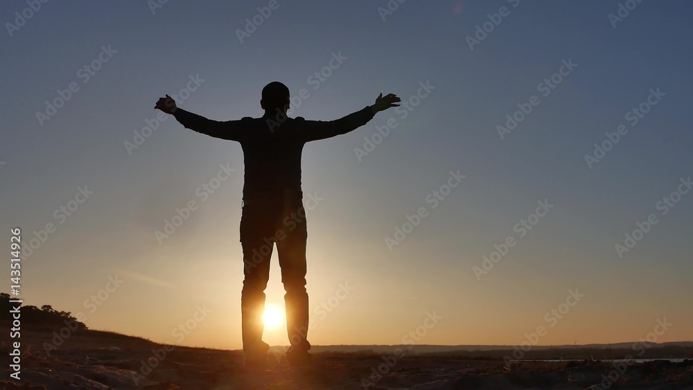 freedom. Man stands on a cliff sunset silhouette hand lifestyle in the sides