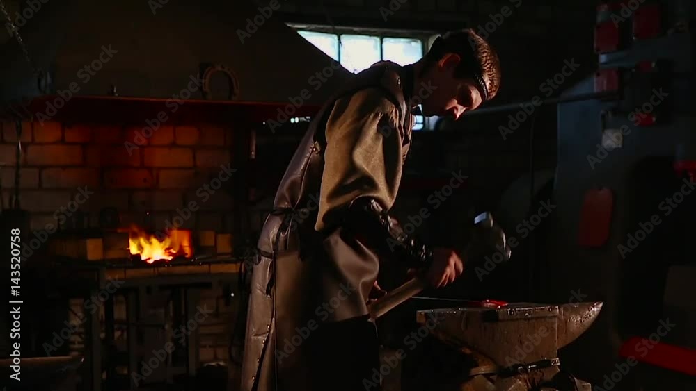 The blacksmith forging the molten metal on the anvil in smithy. The blacksmith forging the molten metal on the anvil in smithy.