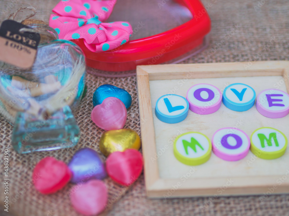 love mom spelled with colorful alphabet blocks and a red heart isolated on wooden board and  sack - Mothers Day