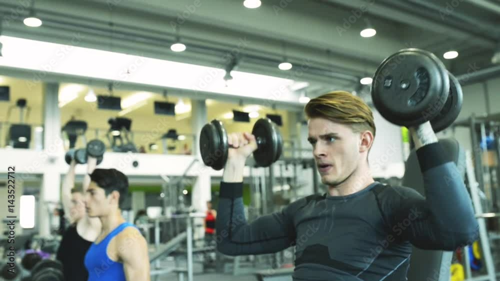 Young men in gym working out with weights. Young men in gym working out with weights.