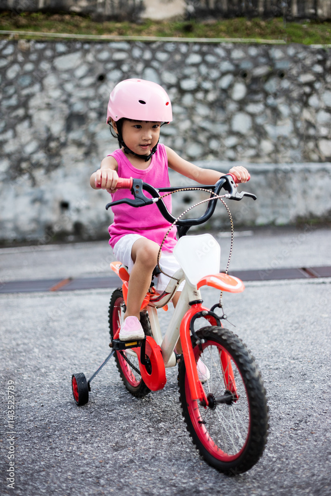 Asian Chinese little girl riding bicycle on tar road