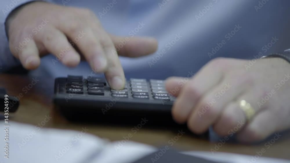 Hand of unrecognizable businessman using calculator - closeup shot Hand of unrecognizable businessman using calculator - closeup shot