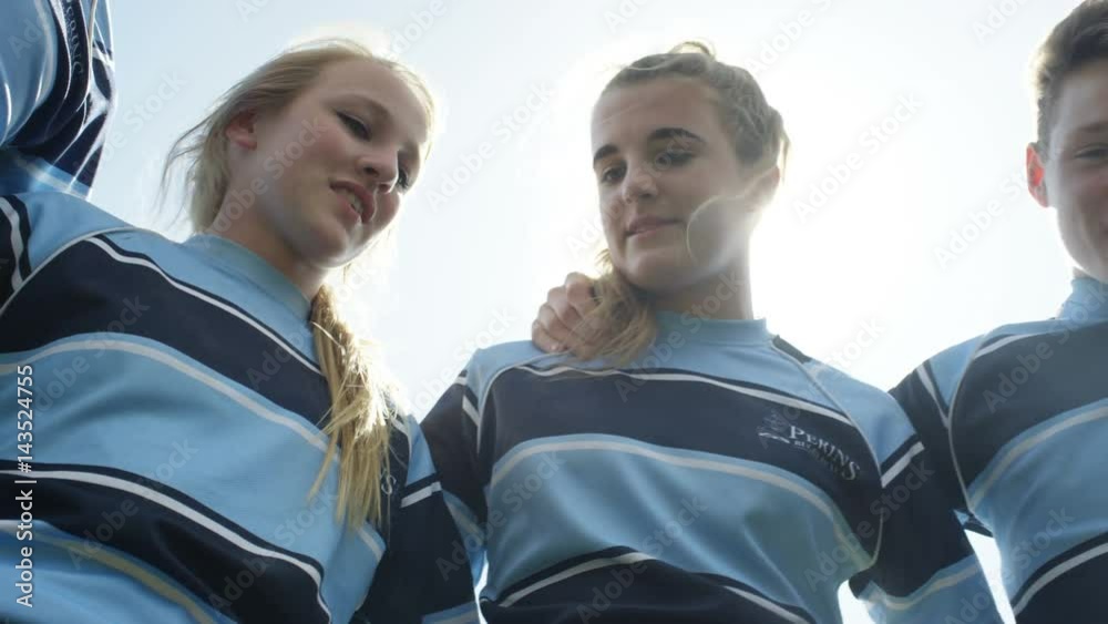  Group of teens in a huddle on school sports field put all hands together