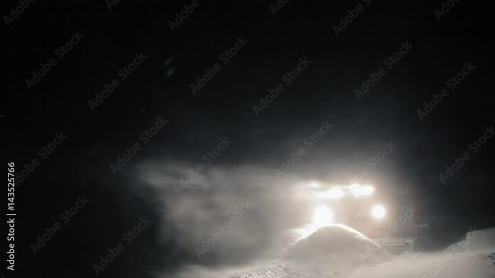 Snowcat preparing a slope at night in high mountains at skiing resort